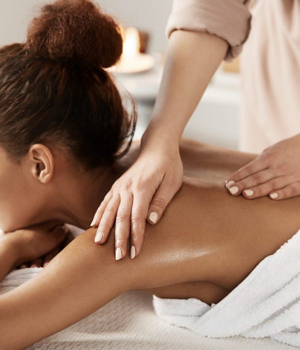 Attractive african girl having massage relaxing in spa salon. Closed eyes.