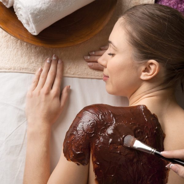 Spa therapy for young woman having cosmetic mask at beauty salon